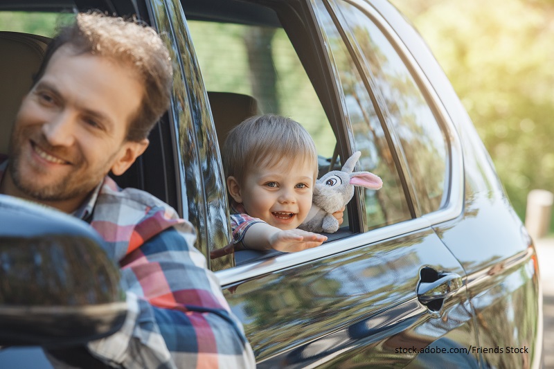 Nachhaltig mobil: Ein Mann ist mit einem kleinen Jungen auf dem Rücksitz im Auto unterwegs.