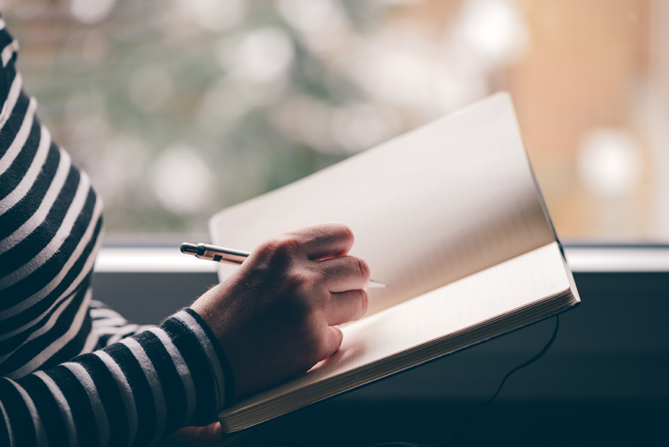 Frau hält ein offenes Buch mit leeren Seiten in der Hand, um ihre guten Vorsätze zu notieren.